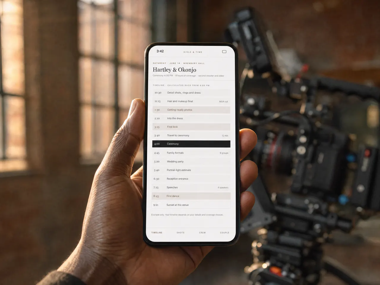 A hand holding a phone showing the coverage timeline, in front of a video camera rig.
