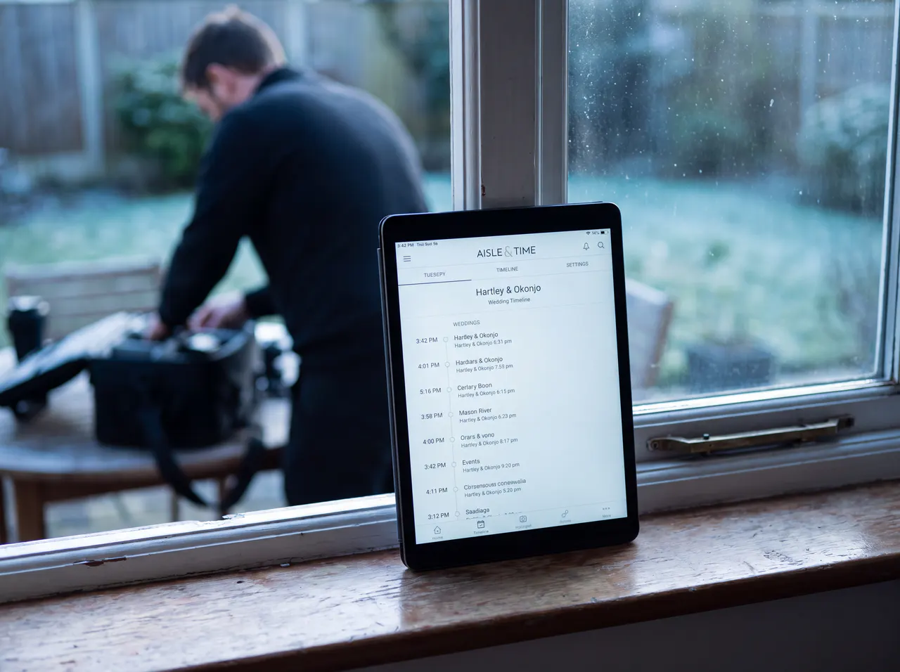A tablet on a windowsill while a photographer packs gear, showing the coverage timeline.
